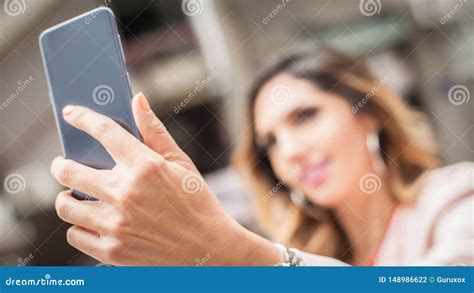 Smiling Young Woman Taking Selfies With Smartphone On City Street Stock