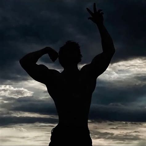 The Silhouette Of A Man With His Hands Up In The Air Against A Cloudy Sky