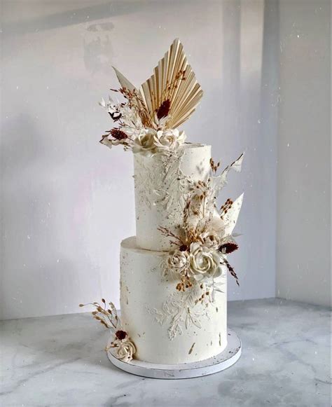 A Three Tiered Wedding Cake With Flowers And Leaves On The Top Sitting