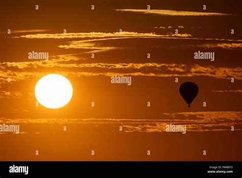 A Hot Air Balloon Floats Above The Wiltshire Countryside As The Sun