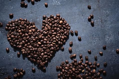 Los granos de café tostados en forma de corazón sobre un fondo gris