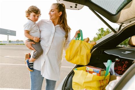 Jeune Femme Tenant Son Fils Debout Dans Le Coffre De La Voiture Photo