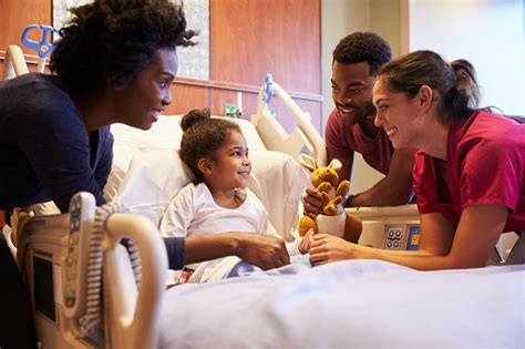 Pediatrician Visiting Parents And Child In Hospital Bed Stock Photo