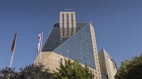 A Very Tall Building With A Clock Tower On It S Side And Flags Flying