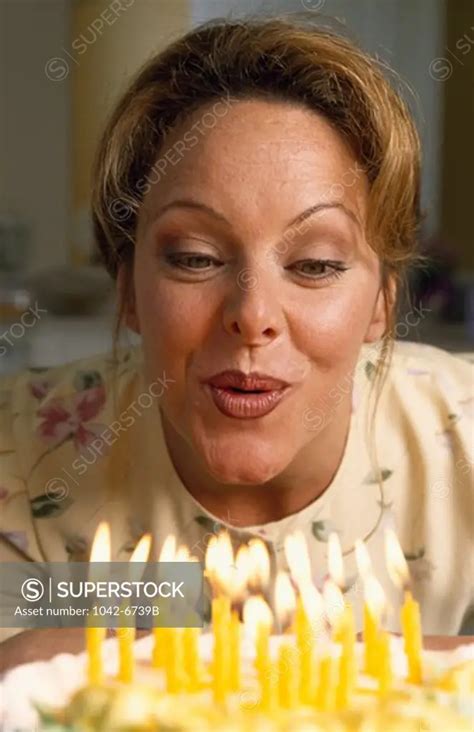 Woman Blowing Out Candles On Birthday Cake SuperStock