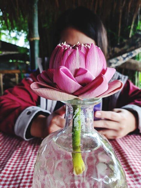 Premium Photo Close Up Of Woman Holding Pink Flower On Table