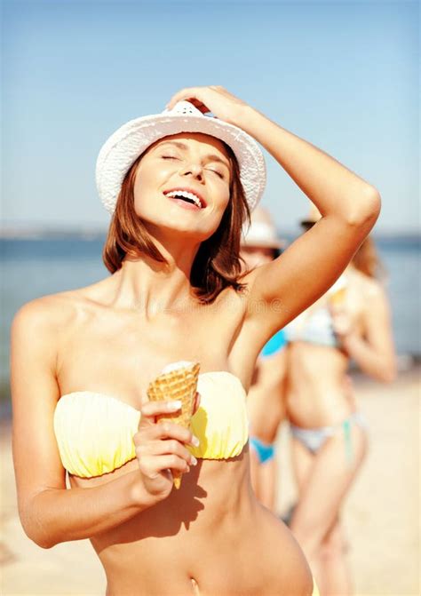 Muchacha En Bikini Que Come El Helado En La Playa Foto De Archivo