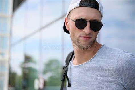 Handsome Young Man With Stylish Sunglasses And Backpack Near Reflection