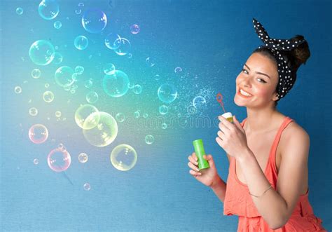 Pretty Lady Blowing Colorful Bubbles On Blue Background Stock Photo