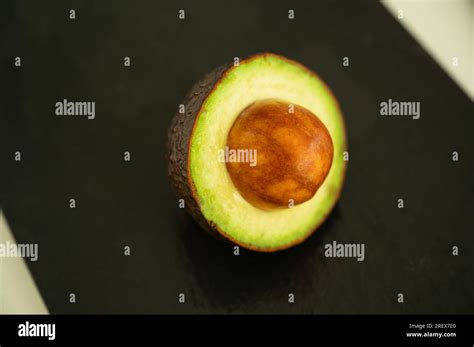 Half Avocado With Seed Sticking Out On Black Background Healthy