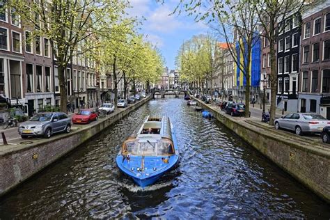 Boat on canal in Amsterdam. A boat moving along a canal in Amsterdam ...