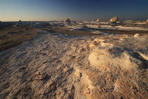 There Is Snow On The Ground And Some Rocks In The Distance With Blue