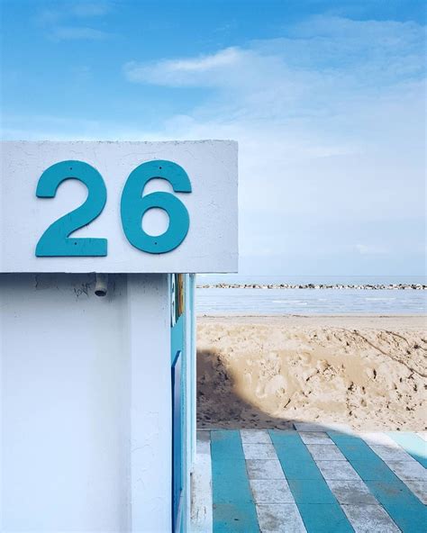 A White And Blue Sign With The Number Twenty Six On It In Front Of A Beach