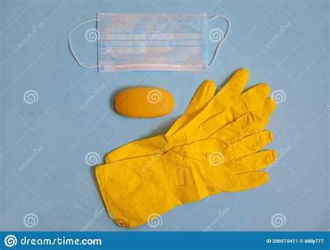 Yellow Rubber Gloves Medical Mask And Yellow Soap Lie On A Blue