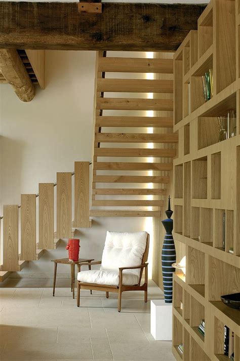 A Living Room Filled With Lots Of Wooden Shelves Next To A White Chair