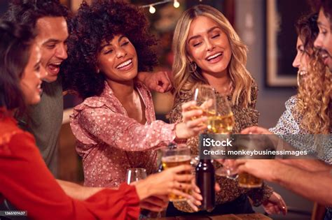 Multicultural Group Of Friends Enjoying Night Out Drinking In Bar