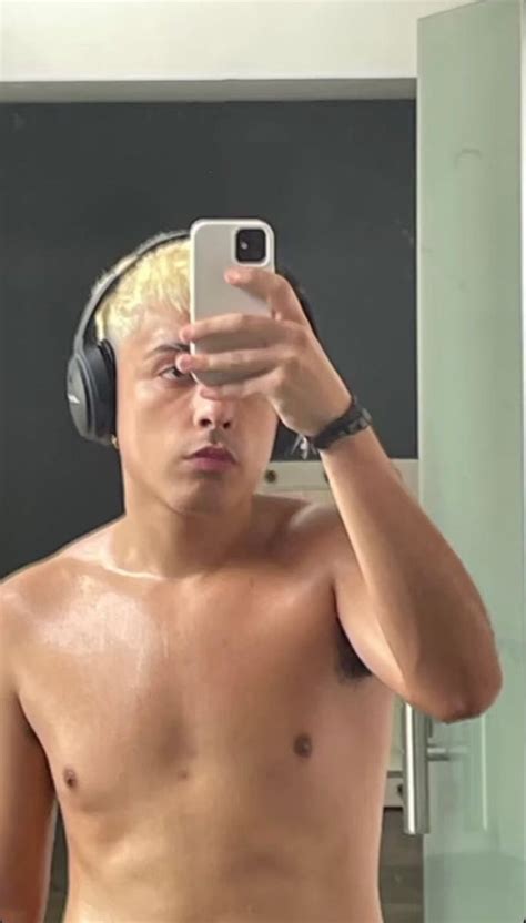 A Shirtless Man With Headphones On Taking A Selfie In Front Of A Mirror