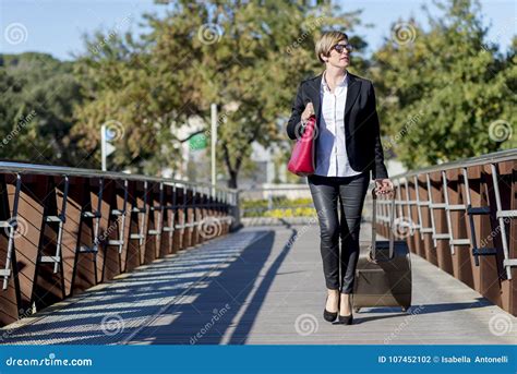 Businesswoman With Trolley Bag Walking In Urban Environment Stock Photo