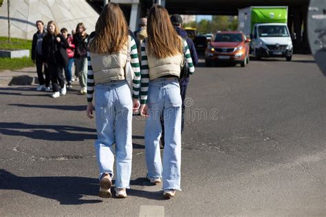 Twins Girls Wearing Same Clothes Are Walking Down The Street Stock