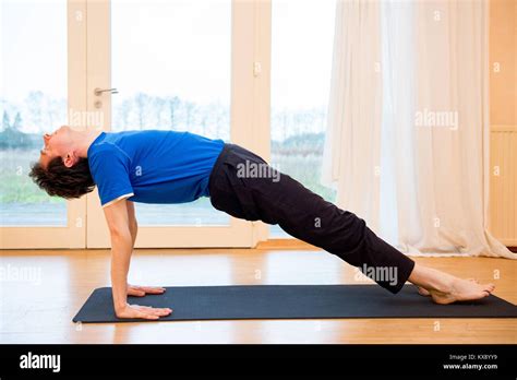 Man Practicing Yoga Indoors In A Retreat Space Doing Upward Plank Pose