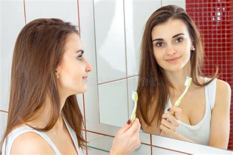 Young Beautiful Woman Brushing Teeth In Front Of The Mirror Stock Image