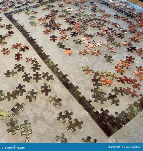 A Puzzle With The Edges Completed On A Leather Looking Table Waiting To