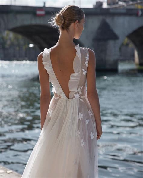 The Back Of A Woman S Dress As She Stands Near Water