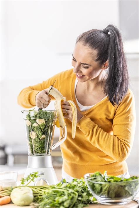 Premium Photo A Woman In The Kitchen Cuts A Banana In A Blender