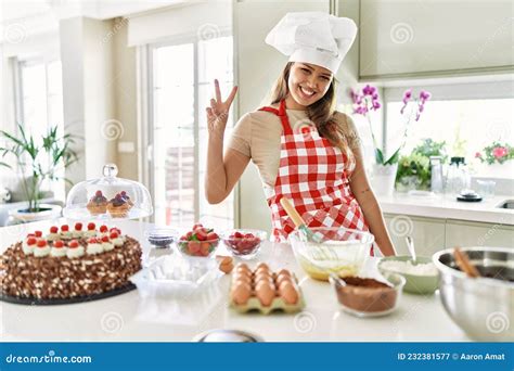 Beautiful Young Brunette Pastry Chef Woman Cooking Pastries At The Kitchen Showing And Pointing