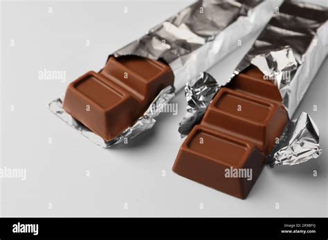 Delicious Chocolate Bars Wrapped In Foil On Light Blue Background