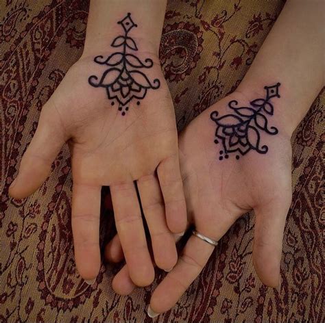 Two People Holding Hands With Tattoos On Their Palms And Fingers Both