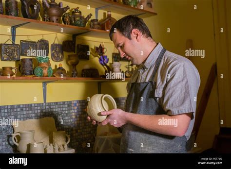 Professional Male Potter Examining Earthenware Pot In Pottery Workshop