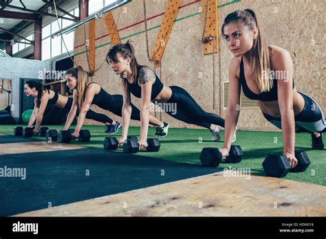 Determined Female Athletes Doing Push Ups On Dumbbells At Health Club