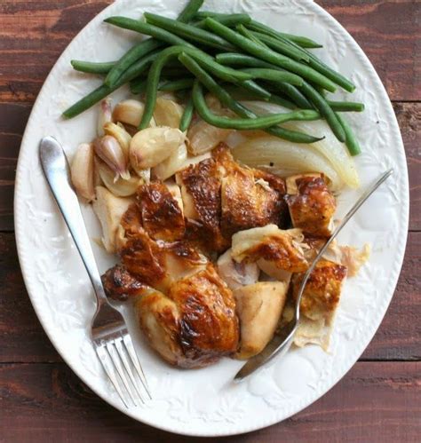 A White Plate Topped With Meat And Green Beans Next To A Fork On Top Of