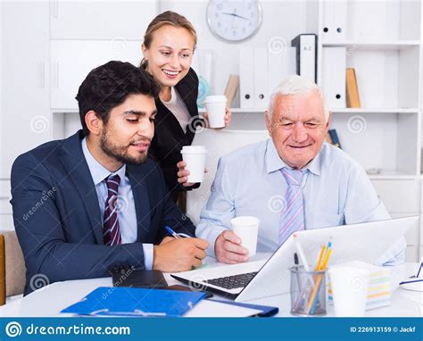 Office Workers Are Demonstrating Reports On Laptop To Mature Boss Stock