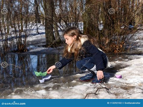 A Little Girl Playing With Paper Boats In Early Spring Semi Frozen