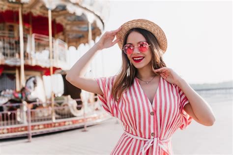 Fille Blonde Joyeuse En Robe Rayée Posant Avec Plaisir Dans Un Parc D attractions Photo Gratuite