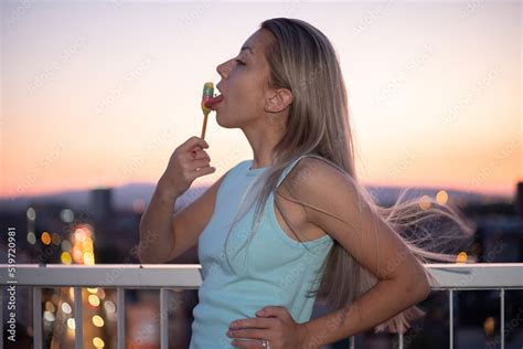 Portrait Of A Sexy Young Woman Licking Ice Cream On The Rooftop Of A