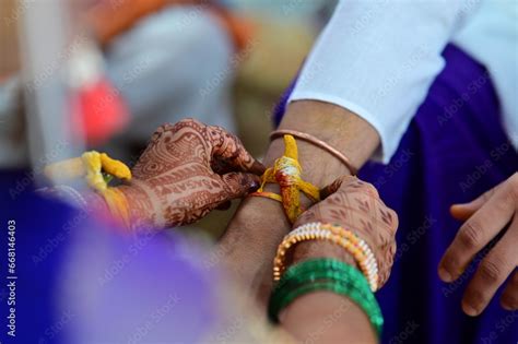 Hands Of Bride Wearing Turmeric Thread On Hand Of Groom In Indian Wedding Ceremony Hindu