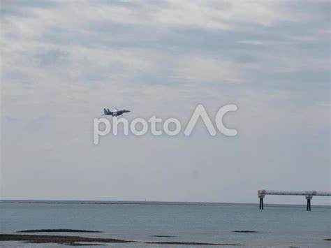 沖縄の瀬長島 のビーチから見た那覇空港（那覇基地）に着陸する戦闘機（f15） No 23122826｜写真素材なら「写真ac」無料