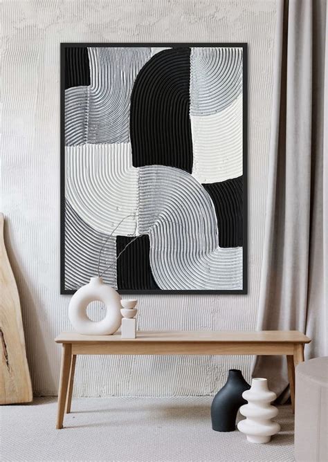 A Black And White Abstract Painting Hangs On The Wall Next To A Table