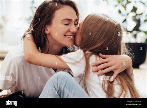 Mom Lovingly Hugs Her Daughter With Her Eyes Closed And Smiling Stock