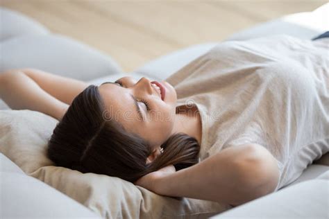 Happy Woman With Hands Behind Head Lying On Comfortable Sofa Stock