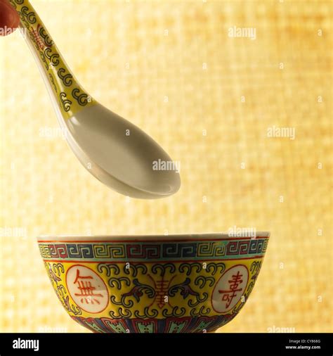 Traditional Chinese soup spoon over patterned bowl with bamboo screen ...