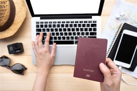 Premium Photo Cropped Hand Holding Passport While Using Laptop On Table