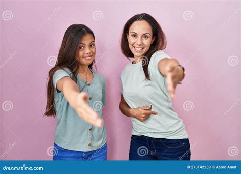 Young Mother And Daughter Standing Over Pink Background Smiling