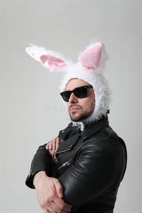 Bearded Man Wearing Bunny Ears And Sunglasses Posing Over White Wall