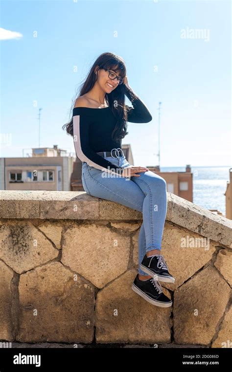 Young Woman Eyeglasses Portrait Sitting On Stoned Bench Smiling Happy Looking To Camera Stock