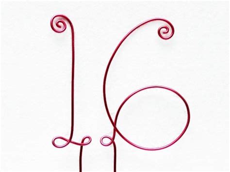 The Letter J Is Made Out Of Wire And Sits On A White Surface With An