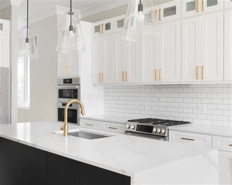 A White And Black Kitchen With Gold Accents And Subway Tile Backsplash